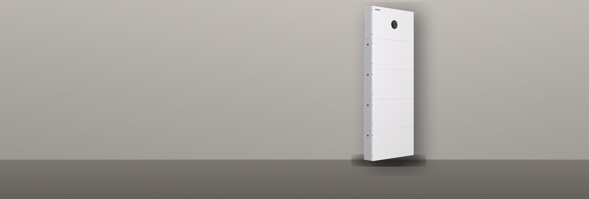 KSTAR BluESpark: stapel van vier accumodules met de omvormer er bovenop, tegen een garagemuur